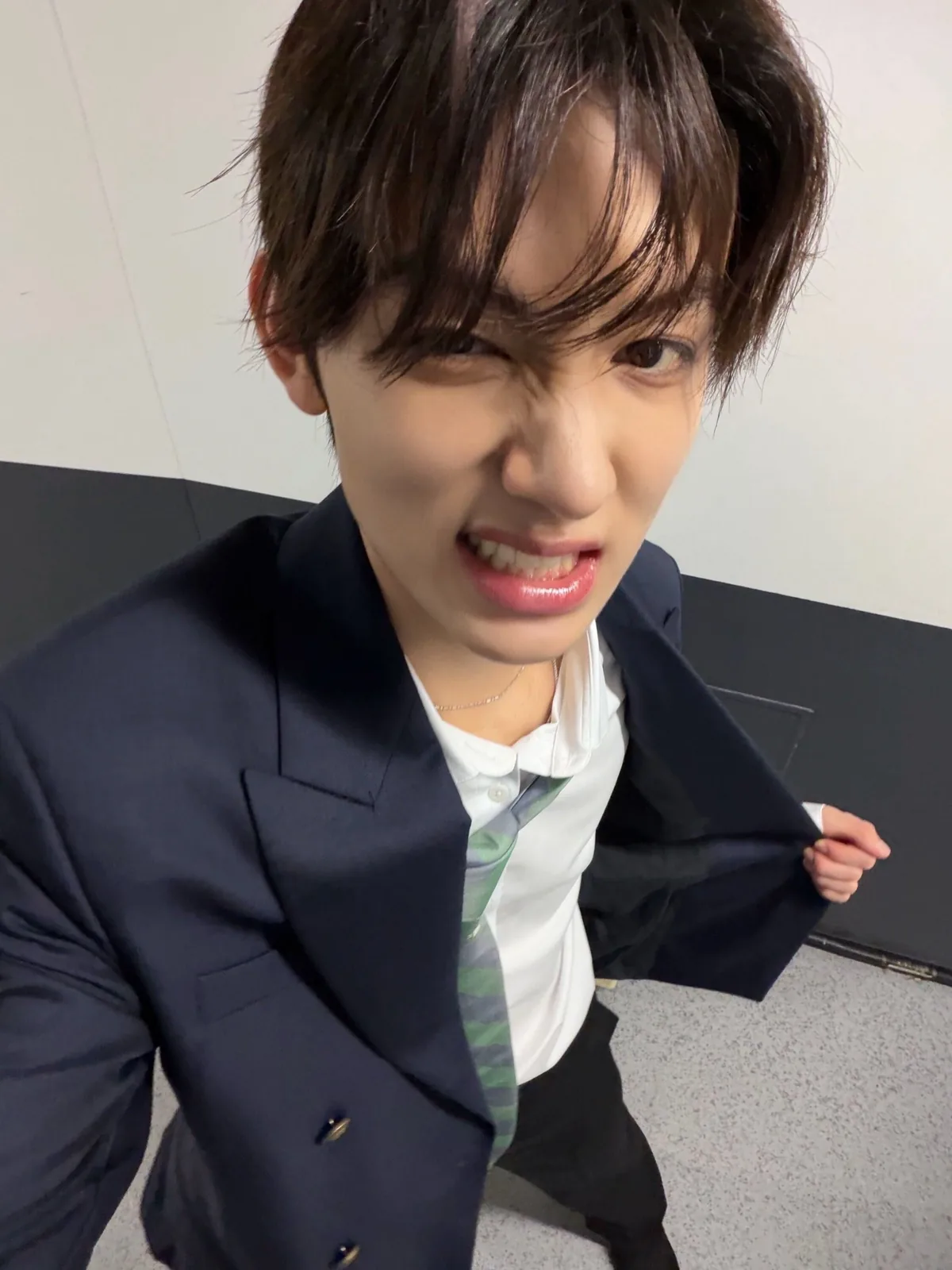Close selfie in a navy suit with a loose green tie